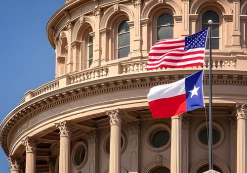 American and Texas state flags flying on the dome of the Texas State Capitol building in Austin